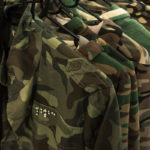 Multiple military jackets hanging on clothes rack