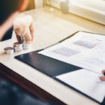 Businessman is adding up all debt on balance sheets while holding stack of coins